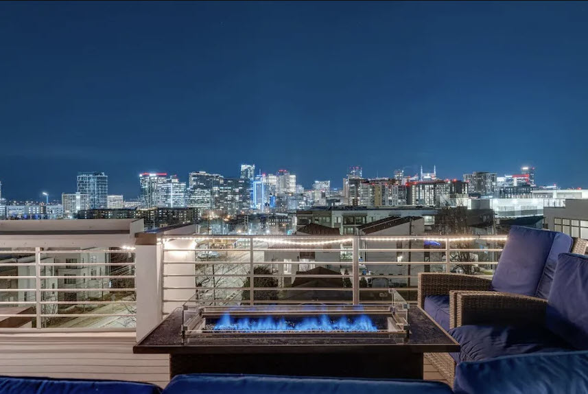 Luxury Nashville Airbnb rooftop with skyline view at night showing downtown city lights and outdoor seating