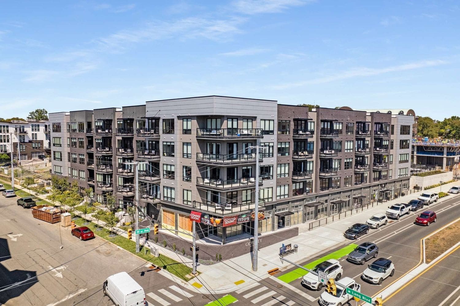The Odyssey Nashville aerial building exterior with ODYSSEY branding and Titos ground-floor retail, Midtown 19th Ave South Music Row top-volume NOOSTR Airbnb investment building